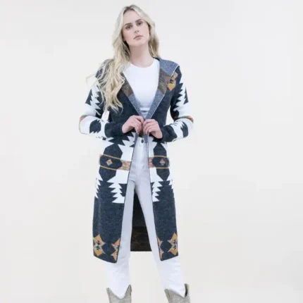 Woman wearing an Aztec print hoodie long cardigan styled with denim jeans and cowboy boots for a cozy western fashion look.